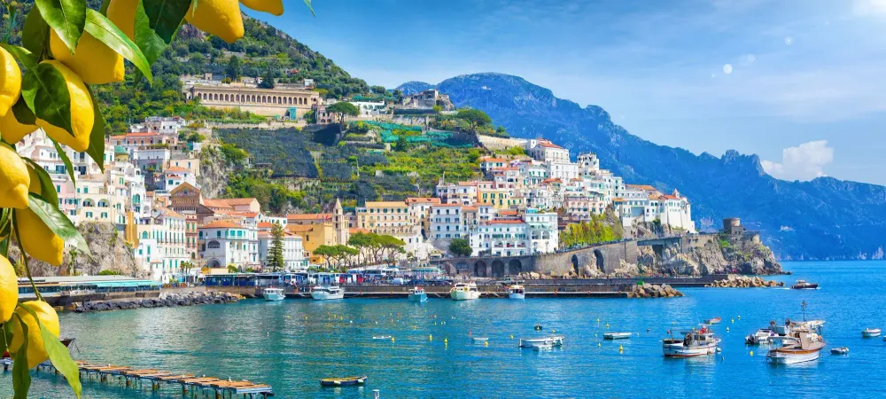 Panoramic view of beautiful Amalfi on hills leading down to coast, Campania, Italy. Amalfi coast is most popular travel and holiday destination in Europe. Ripe yellow lemons in foreground.